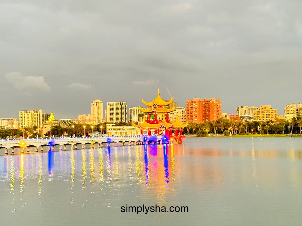 Temple gazebo by the lake with buildings in the background