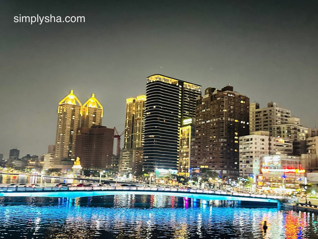 Harbor view with buildings and a bridge at night