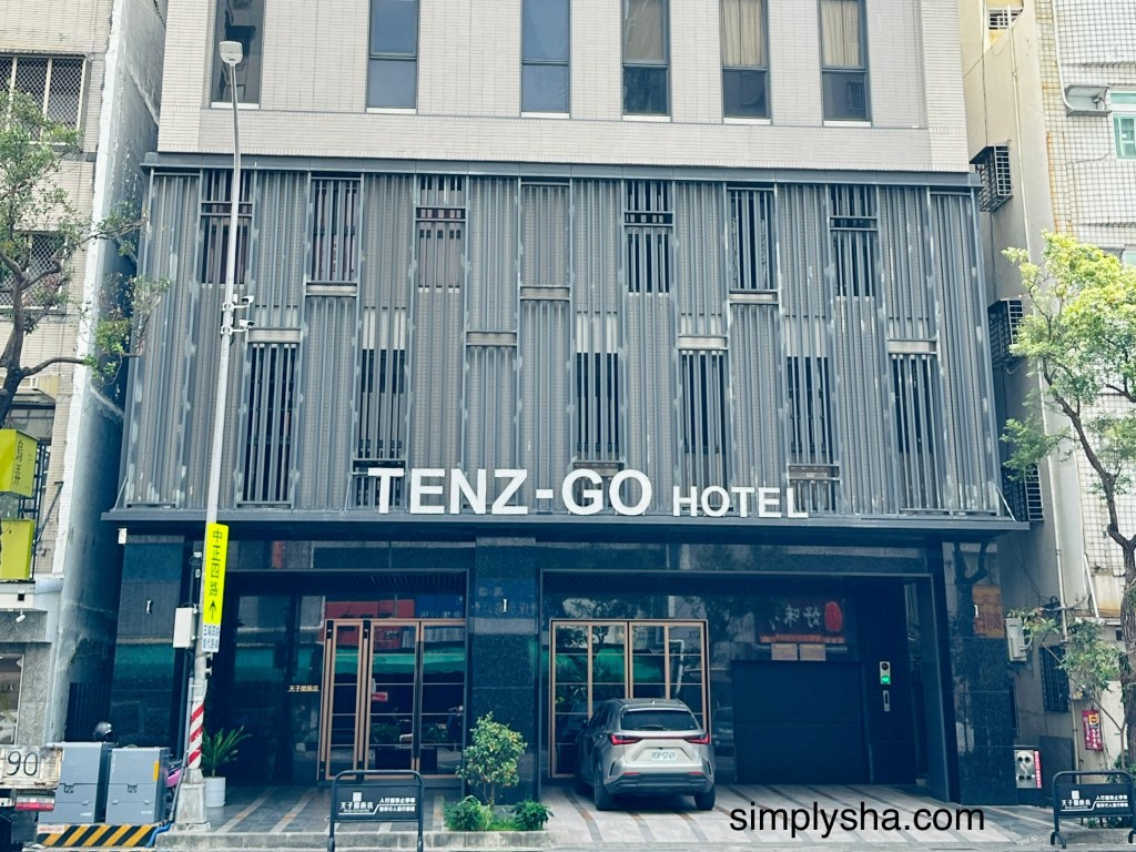 Exterior of Tenz Go Hotel with a gray car parked outside