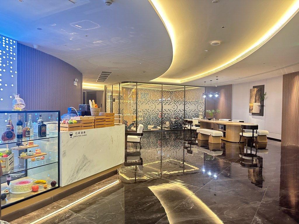 Lounge area in a Guangzhou hotel with pastries, drinks, and modern seating.