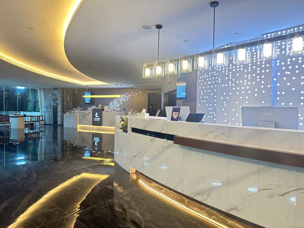 Modern hotel lobby in Guangzhou with marble front desk and ambient lighting.