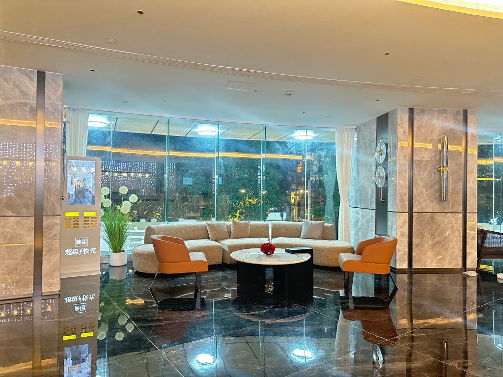 Hotel lobby seating area in Guangzhou with a curved sofa, armchairs, and floor-to-ceiling windows.