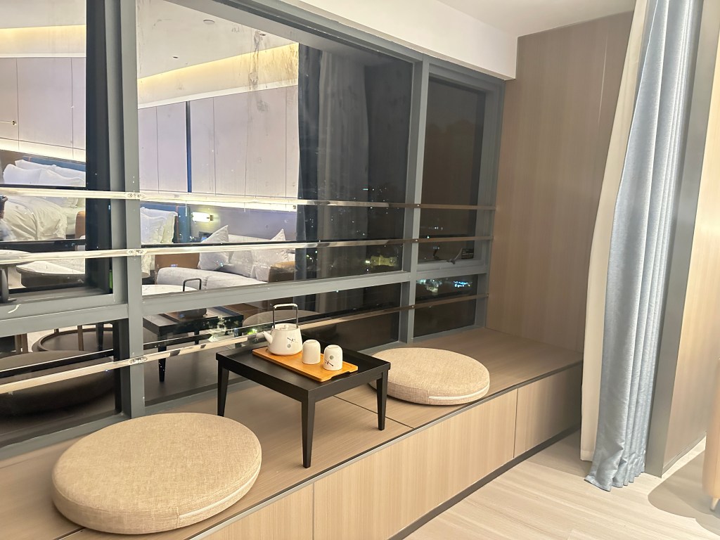 Window seating nook with cushions and a tea set inside a modern hotel room in Guangzhou, China.