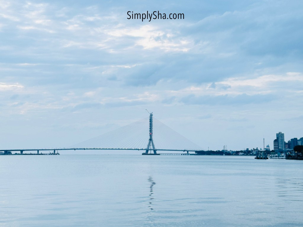 Scenic river view in Tamsui with a bridge stretching across calm waters under a cloudy sky