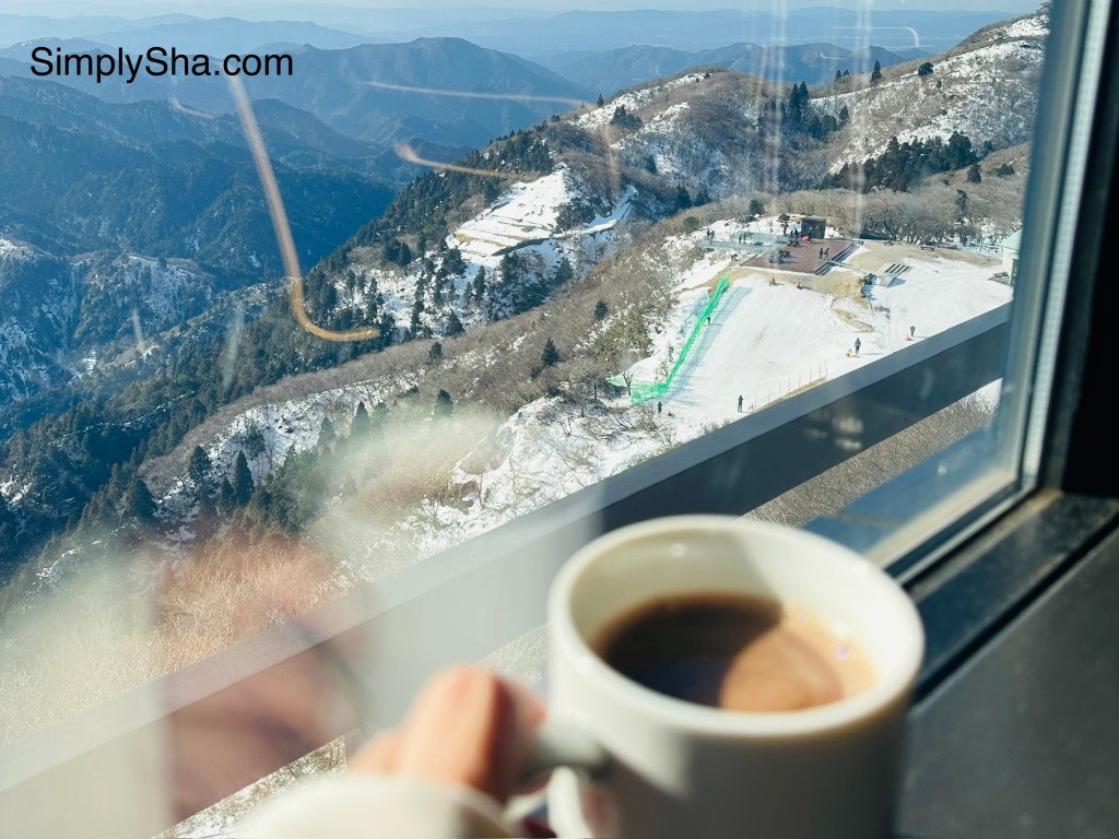 view from Mt. Gozaisho summit with coffee overlooking snow-covered mountains
