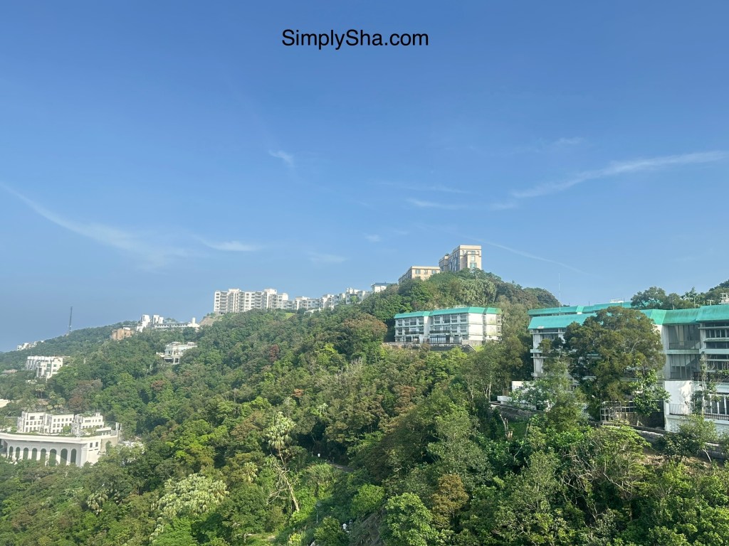 Lush green hills and buildings surrounding Victoria Peak in Hong Kong.